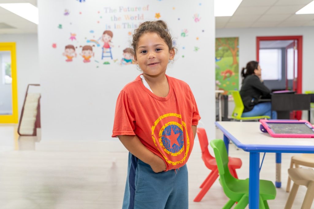 Child with a big, happy smile, posing for the camera at Peek A Boo Pediatric Care, Hollywood, FL.