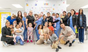 Group photo of the Peek A Boo Pediatric Care team in Hollywood, FL, including doctors, nurses, therapists, and children smiling together