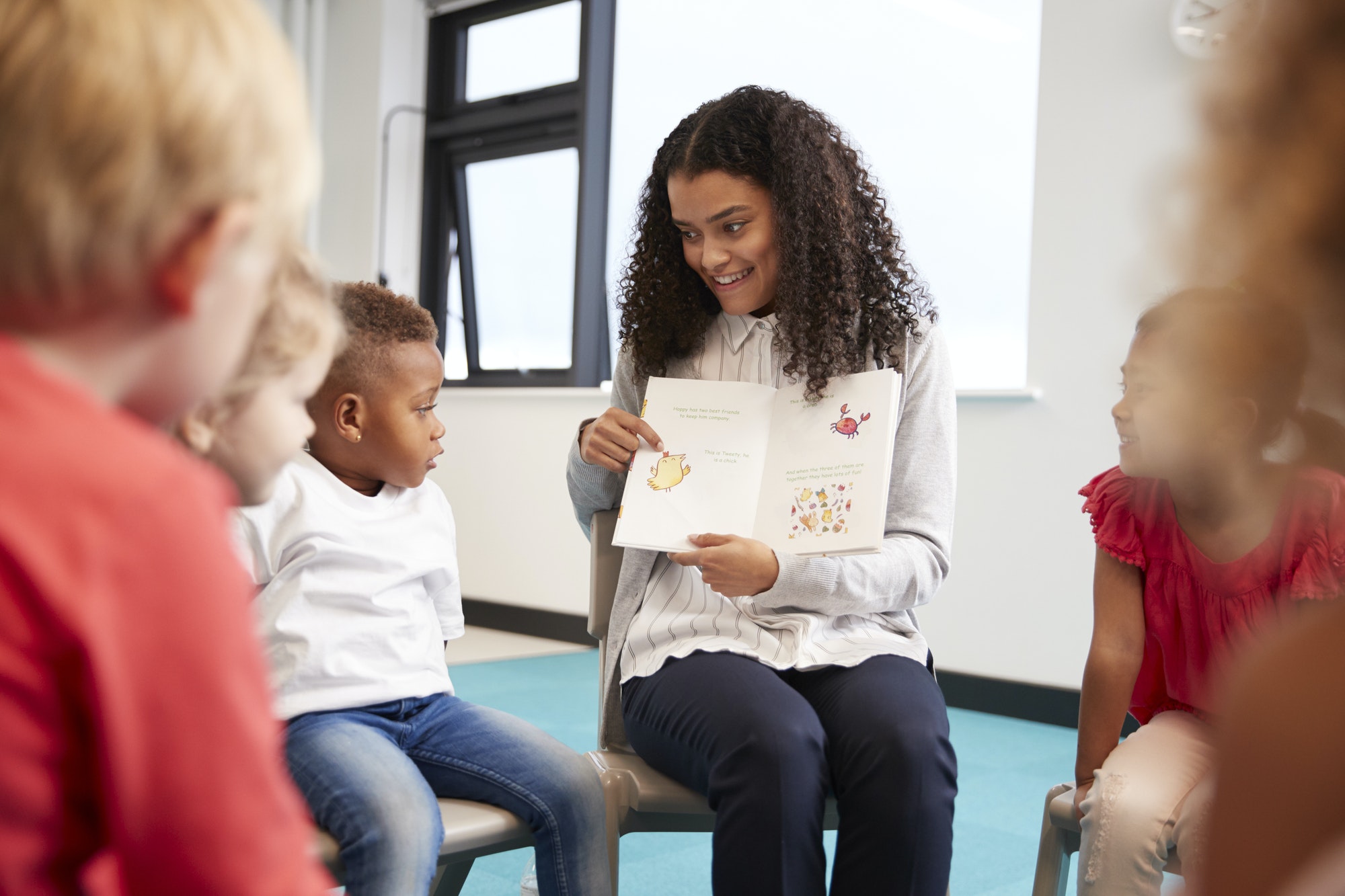 female-teacher-showing-a-book-to-kindergarten-children