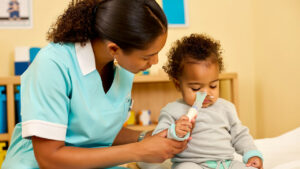 Caring pediatric nurse tending to a medically complex toddler with a gentle nasal cannula at a PPEC