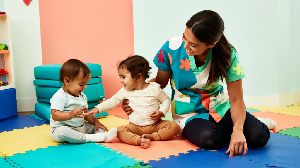 Pediatric nurse playing with two diverse toddlers in a colorful PPEC medical daycare playroom in Hollywood, FL