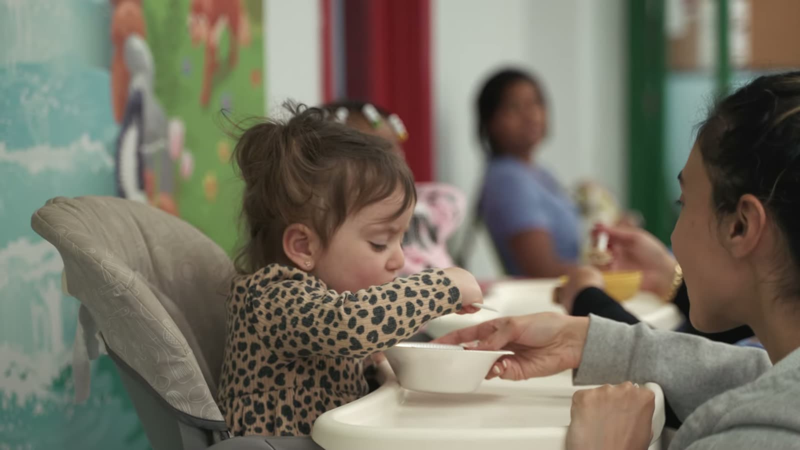 Child at mealtime beside the wall mural at Peek A Boo Pediatric Care in Hollywood, FL