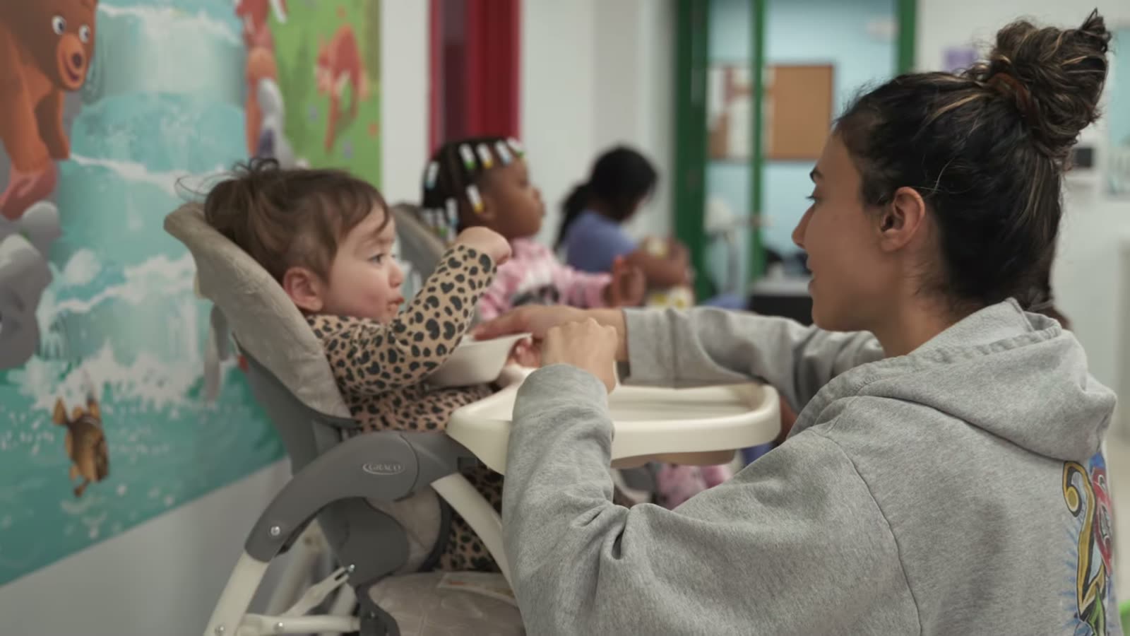A caregiver at Peek A Boo PPEC spoon-feeding a toddler seated in a high chair