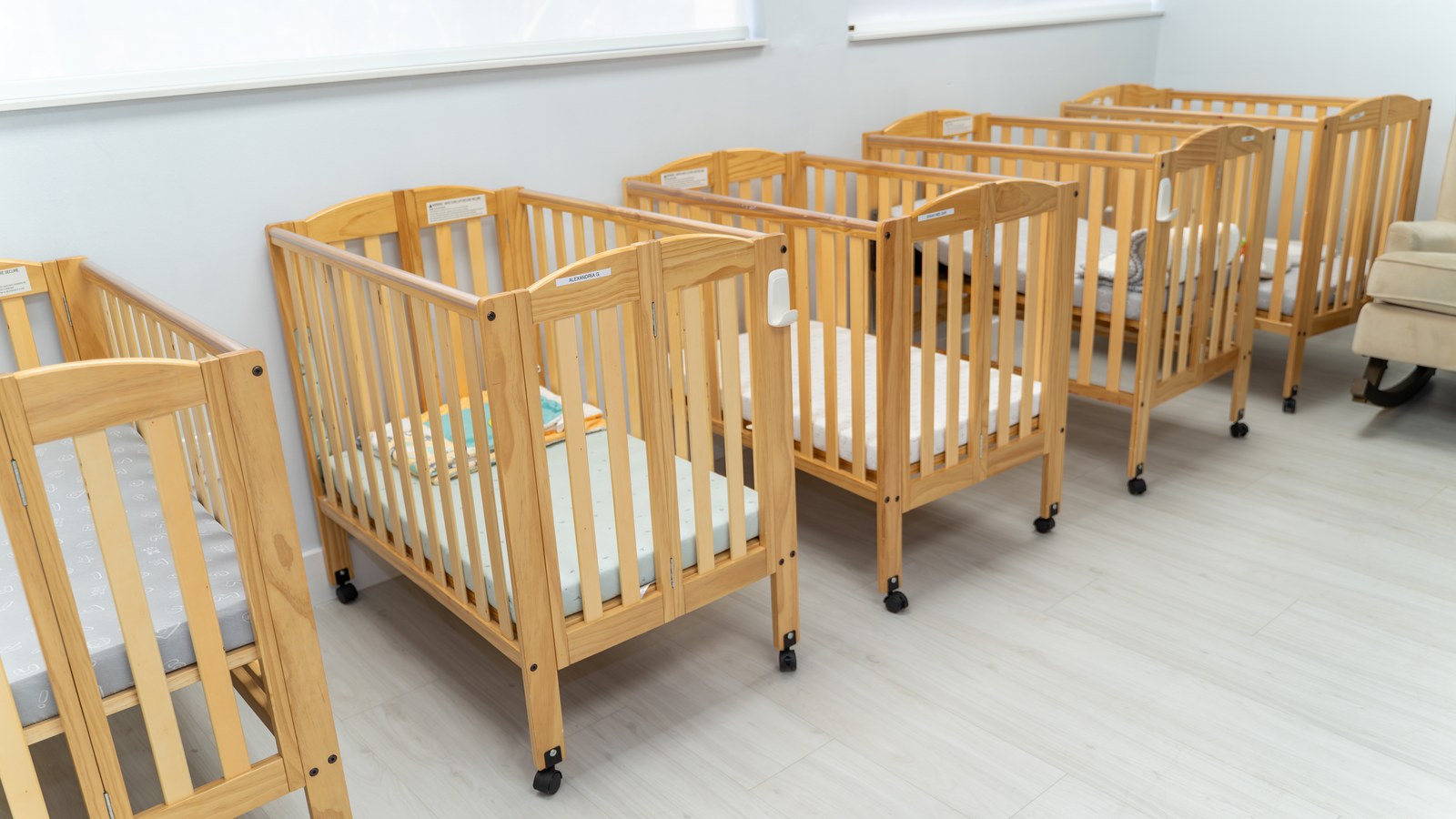 Row of wooden cribs in the infant room at Peek A Boo Pediatric Care in Hollywood, FL