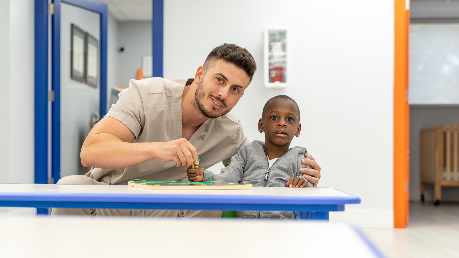 Therapist working one on one with a child at a table during a session at Peek A Boo Pediatric Care in Hollywood, FL